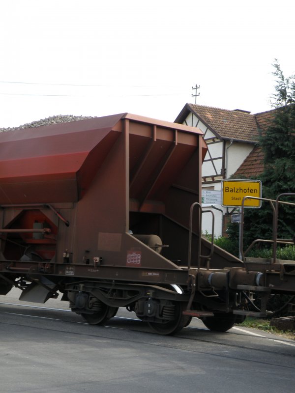 Detailfoto eines Gterzugwaggons direkt vor dem Ortsschild Balzhofen auf einem unbeschranketen Bahnbergang.