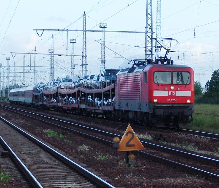 Die 112 120-1 mit DB AutoZug 1451 von Stuttgart/Kornwestheim nach Sassnitz/Mukran Fhrhafen bei der Ausfahrt aus dem Cargo-Bahnhof Rostock-Seehafen.Aufgenommen am 11.06.05 in Hhe Hp Rostock-Dierkow.