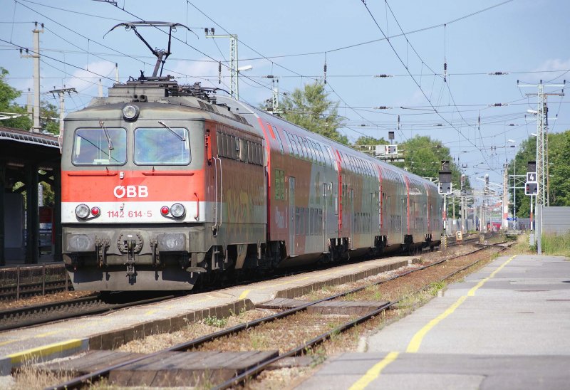 Die an der Seite mit Graffiti beschmierte 1142 614 schiebt am 02.06.2009 ihren REX durch Wien Penzing nach Wien Westbahnhof.