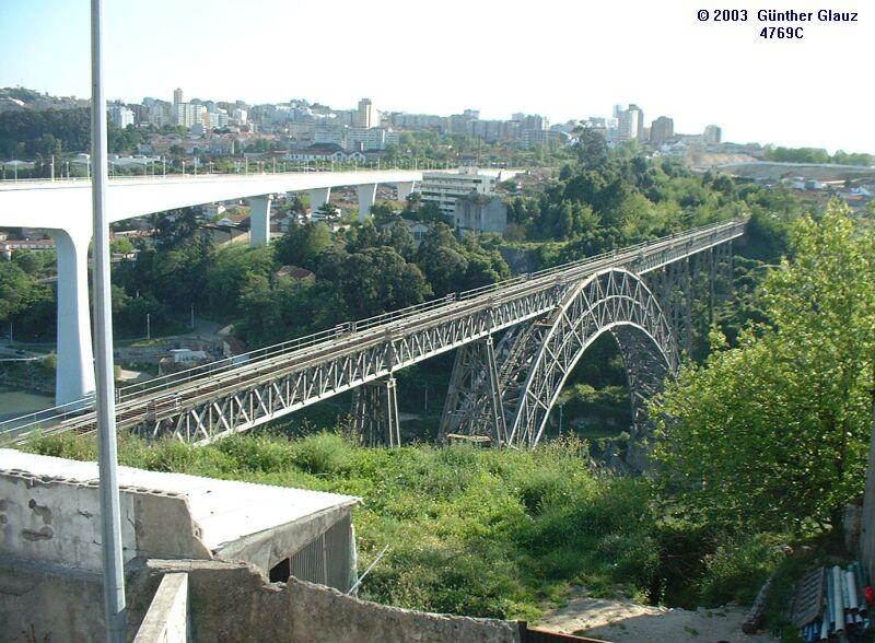 Die beiden Eisenbahnbrcken ber den Rio Doure in Porto am 06.05.2003. Die alte, eingleisige Maria-Pia-Brcke rechts ist nicht mehr in Betrieb, sie wurde von Gustave Eiffel konstruiert und 1876/77 gebaut. ber die neue, zweigleisige Betonbrcke fhrt die Bahnstrecke Porto - Lissabon.