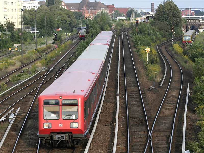 Die Coladose fhrt den anderen S-Bahntypen davon: Die BR485 ist als S9 nach Spandau unterwegs und rollt gerade die Rampe vom Bahnhof Ostkreuz hinunter. Im Hintergrund zu sehen: links BR480 als S75 nach Warschauer Strae, daneben Nachtzugwagen die nach Lichterbeng berfhrt werden; rechts BR481 als S3 nach Ostbahnhof. Alle drei S-Bahnzge werden in krze in den Bahnhof Warschauer Strae einfahren.(!)
(25.08.2007)