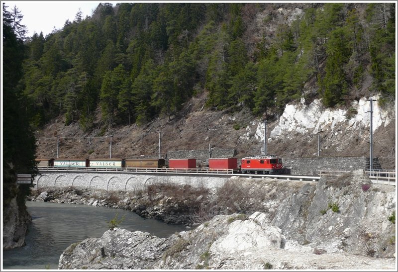 Die Ge 4/4 II 612  Thusis  zieht einen Valser Mineralwasserzug von Ilanz nach Untervaz-Trimmis. Hier befindet er sich in der Rheinschlucht zwischen Trin und Reichenau-Tamins. Zur Zeit werden diese Lehnenviadukte erneuert und sind deshalb mit einem provisorischen Holzgelnder versehen. Links am Felsen hngt die Hochwassermarke mit zwei fast identischen Hchstmarken vom 25.06.1927 und 18.07.1987. (02.04.2009)