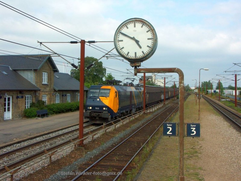 Die grosse Lok passt eben so zwischen die Masten und Zeichen im Bahnhof Taulov. Blick vom Treppenaufgang zum alten Mittelbahnsteig auf den Sdwrts fahrenden Gz. Juli 2009