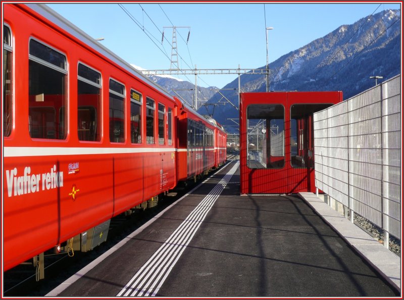 Die Haltestelle Ems Werk wurde erneuert, mit Hochperrons versehen und zum Gelnde der Ems Chemie mit einem hohen Zaun abgegrenzt. Fotografieren durch diesen Zaun ist leider nicht mglich. Ein haltender Be 4/4 Pendel mit einem Wagen in romanischer Beschriftung. (17.12.2007)