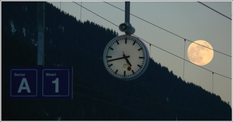Die Hilfikeruhr gehrt zu einem Schweizer Bahnhof wie der Mond zur Erde. Fotografiert in Disentis/Mustr in der Surselva, wo romanisch gesprochen wird. (siehe Tafelanschriften) (10.01.2009)