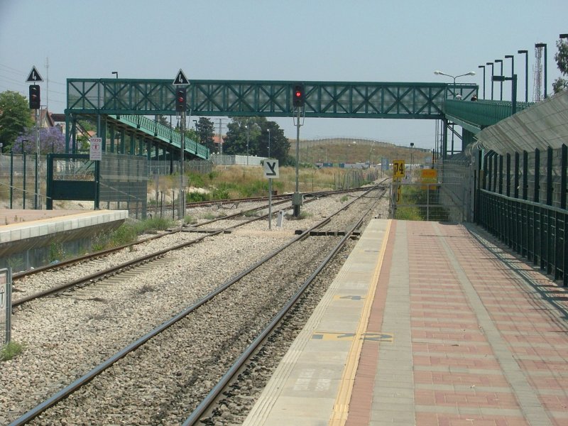 Die markante Fugngerbrcke mit den langen Rampen berspannt die sdliche Bahnhofsausfahrt von Akko, Nord-Israel. Auch in Richtung Sden geht es noch eingleisig, aber in Zukunft wird Akko Bahnknoten. Von hier zweigt die Neubaustrecke in das Herz Galilas ab, nach Karmiel und in ferner Zukunft ber den Golan nach Syrien. (Akko, 14.05.2007)