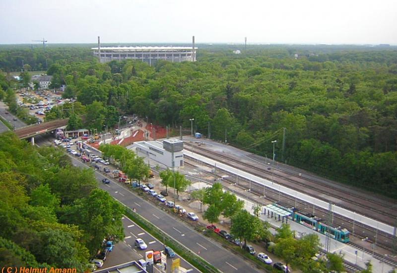 Die M�glichkeit f�r diese Aufnahme besteht nur einmal im Jahr, wenn an Pfingsten das Volksfest W�ldchestag stattfindet. Am Pfingstmontag den 16.05.2005 bestieg ich eine Gondel des Riesenrades, aus der anschlie�end diese Aufnahme entstand. Die Commerzbank-Arena, Heimbasis von Eintracht Frankfurt, thront �ber der Endstation Stadion der Stra�enbahn mit den Abstellgleisen f�r die Verst�rkungsz�ge, ein R-Triebwagen auf der Linie 21 stand gerade am Bahnsteig, am Bildrand links sieht man die Br�cke der DB-Strecke.   