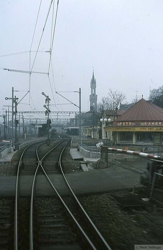 Die Nordausfahrt aus dem Bahnhof Konstanz am 18. Februar 1979, ca 13:20. Das Bild ist bei der Ausfahrt aus dem Schienenbus aufgenommen. Hier hat sich scheinbar nur wenig verndert. Einzig, die Formsignale waren noch in Betrieb, die Unterfhrung hingegen  noch, der Bahnbergang war ME nur ein Ersatzbahnbergang, denn das Orginal war an Stelle der Unterfhrung. Man kann gut erkennen, dass der Bahnsteig damals verlngert wurde. Bitte entschuldigt das graue Wetter.