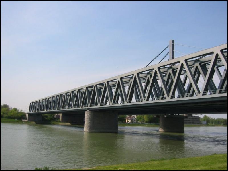 Die Rheinbrcken zwischen Karlsruhe in Baden-Wrttemberg und Wrth am Rhein in Rheinland-Pfalz. Im Vordergrund die zweigleisige Eisenbahnbrcke, die Anfang der 90er Jahre des 20. Jahrhunderts in zwei Abschnitten (pro Gleis) neu gebaut wurde, dahinter die ltere Straenbrcke. Die Bahnbrcke wird von Personen- und Gterzgen genutzt, aber auch von den Zweisystem-Stadtbahnen des Karlsruher Verkehrsverbundes (KVV), die die Region Karlsruhe mit der Pfalz verbindet. Die Aufnahme stammt vom 03.05.2006.