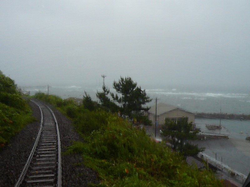Die Sanriku-Bahn (Nordabschnitt): Fahrt im  Retro-Wagen  (4) - der Zug gert in einen schweren Sturm. Durch die vom Scheibenwischer verwischten Regenmassen am Fenster erscheint die Landschaft vllig verzerrt. Bei Shukunohe, 24.August 2008.
