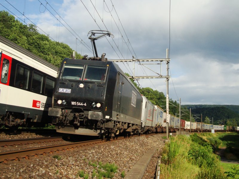 Die schwarze RBH-BR 185 544 und eine 185.2 von Crossrail sind am 09.07.2008 mit dem Ewals-Cargo Care-Zug nach Norden unterwegs zwischen Tecknau und Gelterkinden.