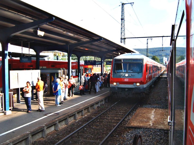 Die Sonne zeigte sich mal von ihrer besten Seite am 23.08.06. Somit kam es vor, dass das Bild ein wenig hell wurde und die Fahrplantafel in diesem Bilckwinkel sehr stark spiegelte. Der stark versptete RE aus Stuttgart Hbf fuhr am diesem sonnigen Augusttag in den Bahnhof Aalen ein. Vorne hing ein stinknormaler Bnrdzf-Steuerwagen.
