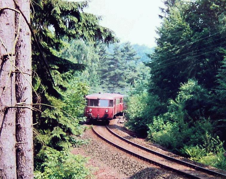 Die Strecke fhrt auf Dmmen und Einschnitten durch ein unwegsames Waldgebiet - Schienenbus aus Grvenwiesbach an der berfhrung der Kreisstrae zwischen Usingen und Wilhelmsdorf, 1. Hlfte der 1980iger Jahre.