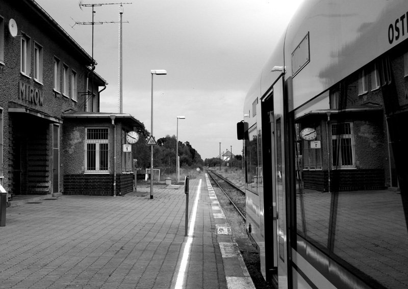 Die Tren vom Triebwagen stehen offen, die vom Bahnhof nicht mehr.
Nach  erfolgreicher  Rationlisierung des Fahrdienstleiters steht das Bahnhofsgebude zum Verkauf.
Mirow,30.07.2008, RS der ODEG nach Neustrelitz.