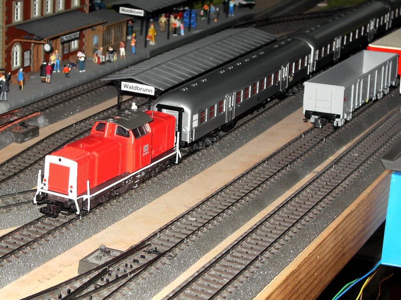 Die V 100 267 mit 3 Silberlingen am Bahnsteig 3 im Bahnhof. 