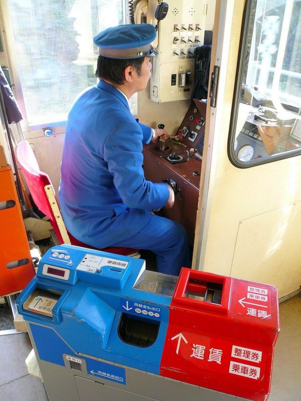 Die Wakasa-Bahn: Der Wagenfhrer von  Kirschblte 1 . Sein Fahrgeld kann man, wie ersichtlich, in aller mglicher Form entrichten (der blaue Teil ist eine Geldwechselmaschine, in den roten Teil kann Papierfahrkarten einwerfen oder Geld, bzw. Geld zusammen mit einem kleinen numerierten Papierstreifen, den man bei der Einstiegstation einem Ausgabegert entnommen hat; der Fahrer steht bei den Stationen auf und kmmert sich um jeden, der nicht weiss wie's geht). 28.Februar 2009. 
