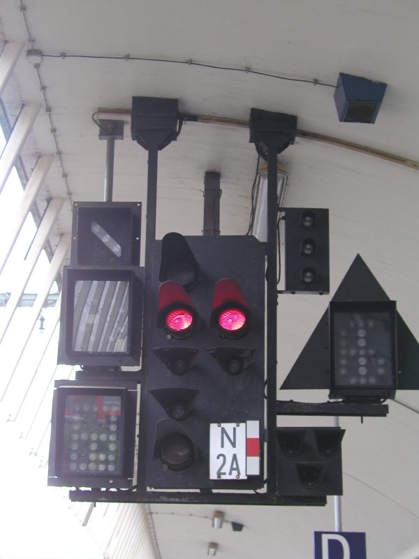 Dieses Hauptsignal h�ngt zusammen mit seinen vielen Begleitern an der Bahnsteig�berdachung des Hbf M�nster. Leider zeigt es hier, verglichen mit den vielen m�glichen Signalbildern, nur ein langweiliges „Halt“.
Links von oben nach unten sind Fahrtanzeiger, Zp9 und Richtungsanzeiger montiert. In der Mitte befindet sich das eigentliche Hauptsignal. Es kann alle drei Signalbilder sowie Sh 1 und Kennlicht zeigen. Rechts von oben nach unten befinden sich Bremsprobesignal, Geschwindigkeitsanzeiger und Vorsichtsignal.
(Aufgenommen am 5.10.2006)
