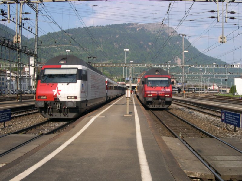 Dieses Schauspiel wiederholt sich regelmig und tglich jede Stunde in Arth Goldau. Links der Zug mit der Werbelok 460 090 ist der EC 109 Basel-Mailand, rechts der Zug mit der roten 460 115  Heidiland  ist IR 2261 Zrich-Locarno. Dieser Zug fhrt am Schluss auch einen Panoramawagen der 1. Klasse, wie fast alle IR´s auf der Gotthardbahn. Im Hintergrund ist die Rigi, die Knigin der Berge, zu erkennen. Die blauen Zge der (Arth-)Rigi-Bahn fahren immernoch auf dem Hochbahnsteig ber den Gleisen 5-8 in Arth-Goldau ab. Auch dieses ist im Hintergrund zu erkennen.