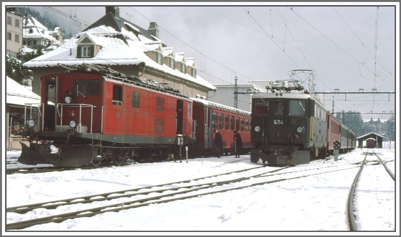 Disentis/Mustr noch ohne Hochperrons und Bansteighalle. Ge 4/4 I 604  Calanda  noch mit grnem Wagenmaterial bringt Anschlussreisende fr den FO Zug mit HGe 4/4 36. Es liegt bereits Schnee am 14.10.1975.