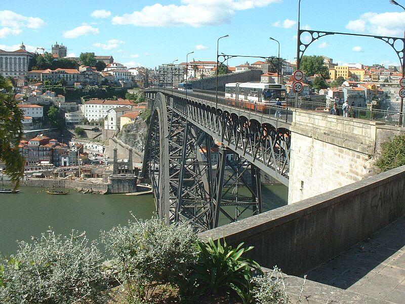 Dom-Luis-Hochbrcke in Porto ber den Rio Doure mit zwei Fahrbahnen, unten und oben, am 06.05.2003. Oben, wo jetzt die beiden Omnibusse fahren, soll in einen Jahr Portos Metro fahren, allerdings wurde bis jetzt noch nicht mit den Umbauarbeiten an der Brcke begonnen. Die Brcke wurde von Theophile Seyring konstruiert und von 1881 bis 1886 gebaut. 