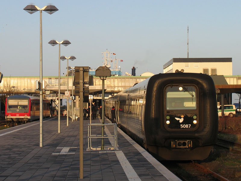 DSB Gumminase 5087 hat als EC 36 auf der Vogelfluglinie von Koebenhavn �ber R�dbyhavn kommend die Scandlines-F�hre verlassen, um nach Hamburg weiterzufahren; im Hintergrund steht der als RB 21916 aus L�beck angekommene 928 685; Puttgarden, 19.12.2008
