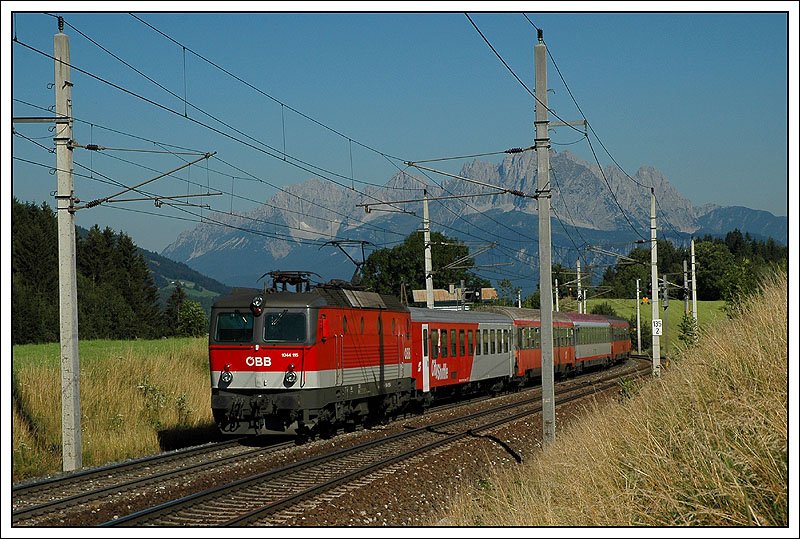 Durch die Ennstalsperre werden mit Ausnahme des Zugpaares 668/669 zwischen Bischofshofen und Innsbruck alle Zge mit den Triebwagen der Rh 4010 gefahren. Aufgrund des Ausfalles eines 4010ers kann der Umlauf 515/512/613/610 derzeit nicht wie geplant mit dieser Baureihe gefhrt werden. Als Ersatz wird ein gemischter 6-teiliger Wagensatz bespannt mit der Reihe 1044 herangezogen.
Mit dem Wilden Kaiser im Hintergrund sieht man auf dem Foto 1044.115 mit IC 515 am 16.07.2007 zwischen St.Johann und Fieberbrunn.