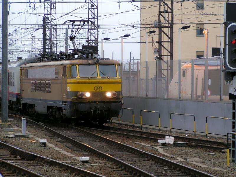 E-Lok 1608 im gold/gelben M�rklin Look, f�hrt mit ihrem Zug in den Bahnhof von Bruxelles Midi ein. Im Hintergrund sieht man den Triebkopf eines Eurostar. 07.03.08