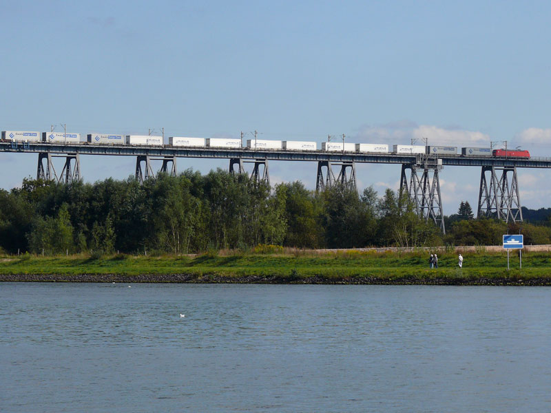Ein Containerzug hat aus Richtung Flensburg kommend die Hochbrcke ber den Nord-Ostsee-Kanal passiert. Zuglok ist wahrscheinlich eine BR 185; Rendsburg, 16.09.2009
