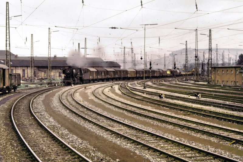 Ein langer Dampf-Gterzug, gezogen von einer 050er, verlsst den Bahnhof von Heilbronn in Richtung Stuttgart. Links im Hintergrund das BW und rechts im Hintergrund der Wartberg, Heilbronns Hausberg. Das Bild entstand Anfang der 70er Jahre.