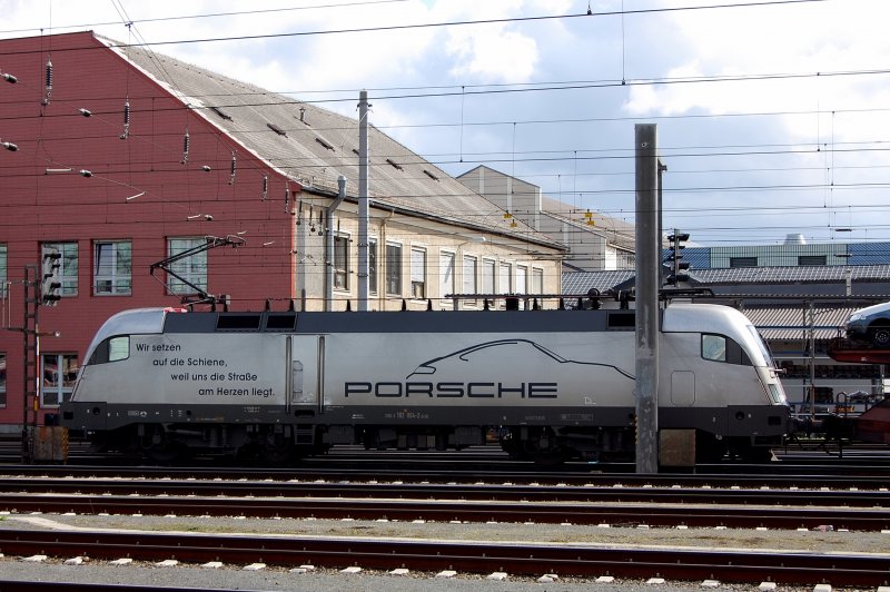 Ein  Porsche  mit 4 Achsen? So etwas gibt es nur bei der Bahn. 182 004-2 zieht einen Autozug mit Konkurrenzprodukten aus dem Bahnhof von Linz. 