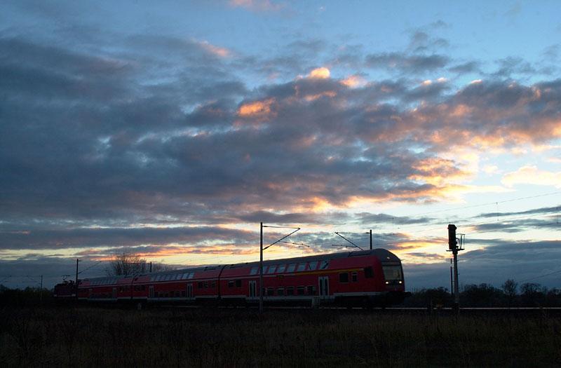 Ein Regionalzug der Linie Magdeburg - Lutherstadt Wittenberg passiert an einem Herbstabend im letzten Sonnenlicht das Einfahrtsignal von Rolau (Elbe).