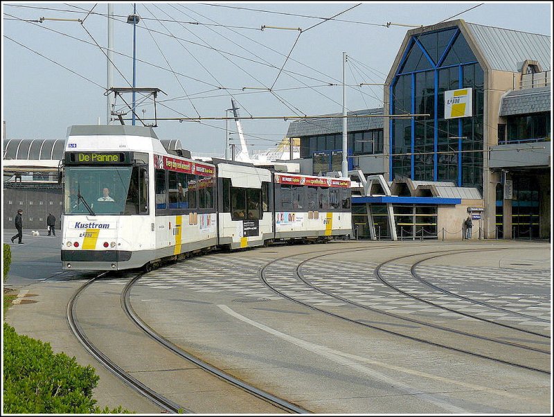 Ein Stra�enbahnwagen des Kusttram verl��t am 12.04.09 die Haltestelle Oostende Station in Richtung De Panne vor der Kulisse der F�hre nach England, welche im Hafen von Oostende liegt. (Hans)