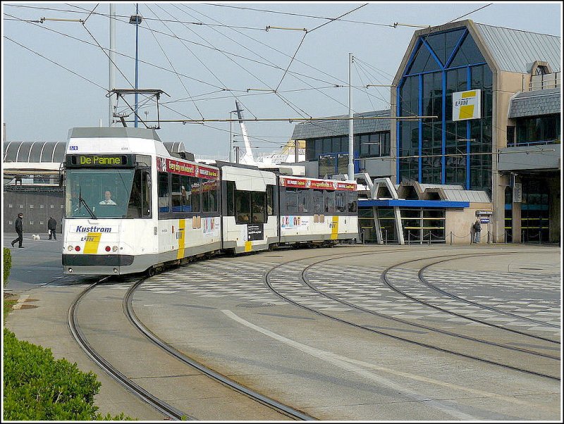 Ein Straenbahnwagen des Kusttram verlt am 12.04.09 die Haltestelle Oostende Station in Richtung De Panne vor der Kulisse der Fhre nach England, welche im Hafen von Oostende liegt. (Hans)