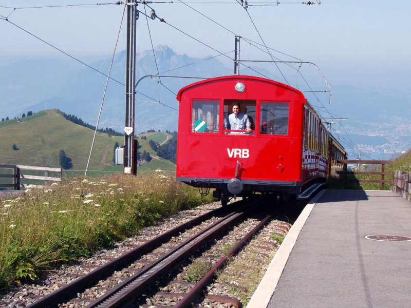 Ein Zug mit zwei Beiwagen kommt in Rigi Kulm an.