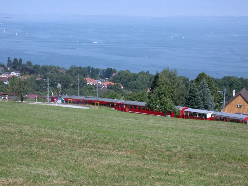 Ein Zug der RHB unterhalb Wartensee. (13.07.2003) Im Hintergrund ist der Bodensee zu sehen oder wie hier an dunstigen Tagen auch Schwbisches Meer genannt.
