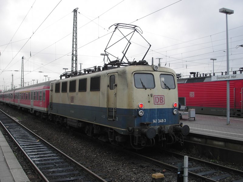 Eine blau-beige E-Lok der DB-Baureihe 141 mit verkehrsroten Silberlingen im sdlichen Kopfbahnhofsbereich des Dortmundter Hautbahnhofs am 09.01.2004.