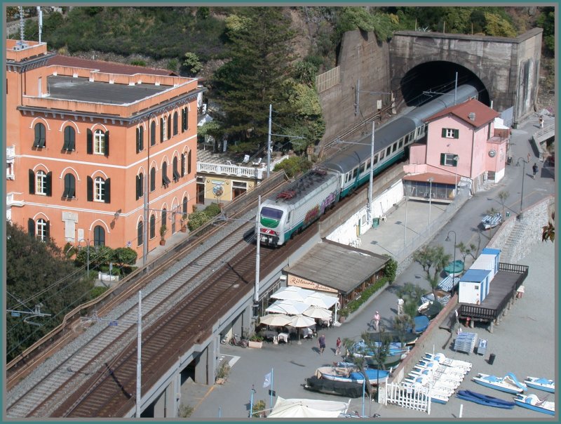 Eine E402 erscheint mit ihrem IC aus einem der vielen Tunnels bei Monterosso. Interressant ist, dass sich ca. 20m hinter dem Tunnelportal zwei einspurige Tunnelportale verstecken. Das Meerseitige Geleise wurde zuerst gebaut und weist deshalb mehr Kurven und mehr offene Strecken auf.(27.04.2007)