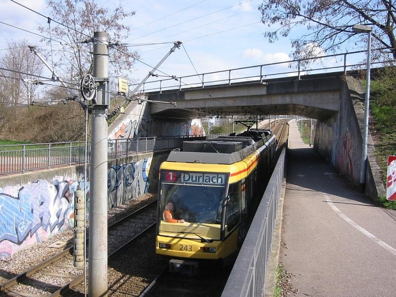 Eine Niederflurstraenbahn, eingesetzt auf der Linie 1 zwischen den Karlsruher Stadtteilen Durlach und Oberreut, hat am 29.03.2005 gerade die Haltestelle Hardecksiedlung in Richtung Innenstadt und weiter nach Durlach verlassen. Sie unterquert dabei die Eisenbahnstrecke von Karlsruhe in die Pfalz. Gleich dahinter wird die Straenbahn eine Rampe mit 6 % Steigung zu einem Brckenbauwerk hochfahren, das zwischen der Hardecksiedlung und der Europahalle ber eine Lnge von gut 500 Metern ein Gewerbegebiet, eine Stadtschnellstrae (die Sdtangente) sowie die Gnther-Klotz-Anlage mit dem Flsschen Alb berquert.