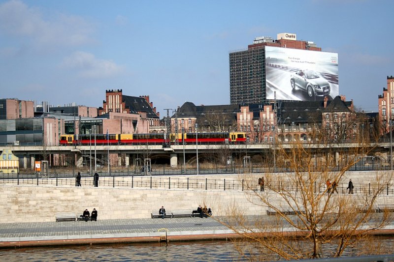 Eine Panorama S-Bahn zwischen Berlin-Hauptbahnhof und Bahnhof Friedrichstrasse. Im Hintergrund das Charite Krankenhaus, dessen Fassade mit Werbung verkleidet wurde das das Bettenhaus gerade renoviert wird. Im Vordergrund die Spree. Das Besondere an der Panoramabahn ist die offene Sicht durch die Rundverglasung und die Erkl�rungen eines Stadtf�hrers.