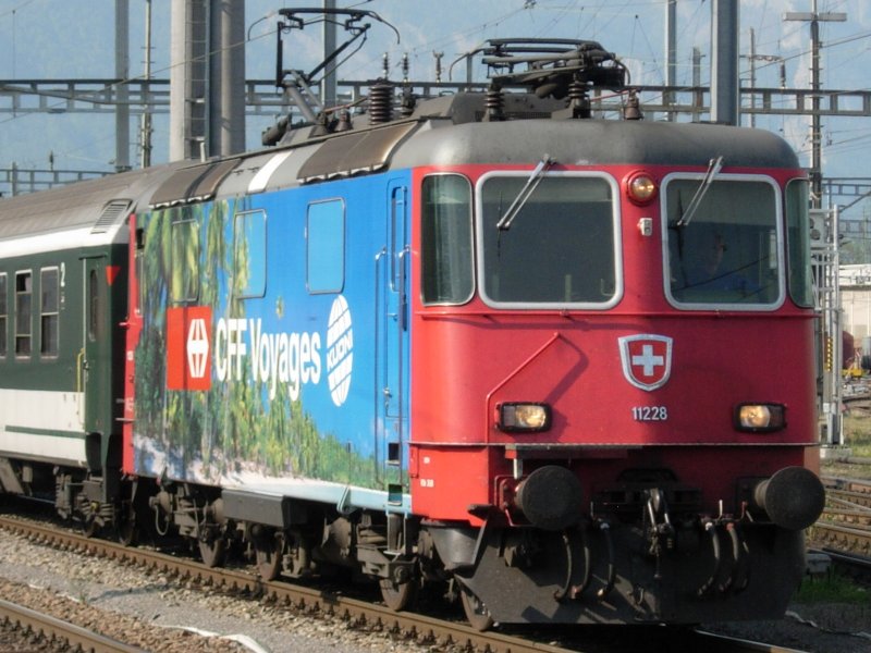 Eine RE 421 ( RE 4/4 II ) mit Werbung fr die SBB Reisebros zieht gerade einen Rheintalexpress ( REX ) aus dem Bahnhof Buchs / SG von St.Gallen nach Chur. 