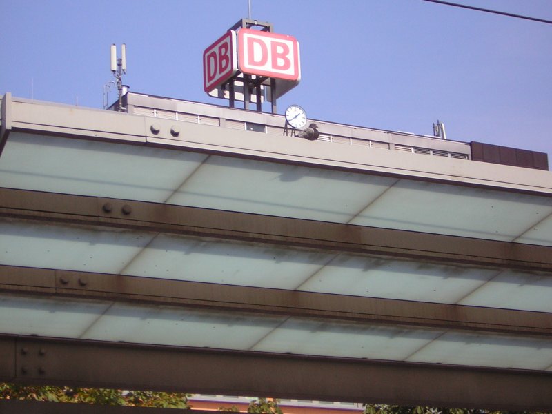 Eine Taube bei der Pause vorm Deutsche Bahn Schild und Uhr.