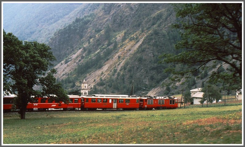 Eine der zwei Gem 4/4 und ein ABe 4/4 fahren mit dem BerninaExpress nach Tirano, hier in der S-Kurve oberhalb des Bahnhofs Brusio. (Archiv 08/84)