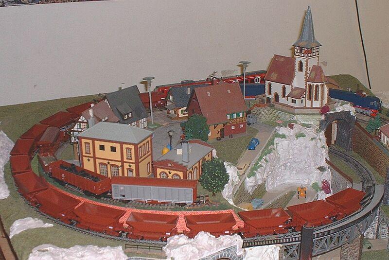 Erzzug mit 16 Wagen Uadp und der ROCO-Lok IORE 101/102 (Hinter der Kirche). Da die Kupplungsnachbildung SA3 eine Kurzkupplung ist, macht der Zug auch im Radius 358 einen guten Eindruck. Der erste Wagen hinter der Lok mu eine normale Hackenkupplung haben. 