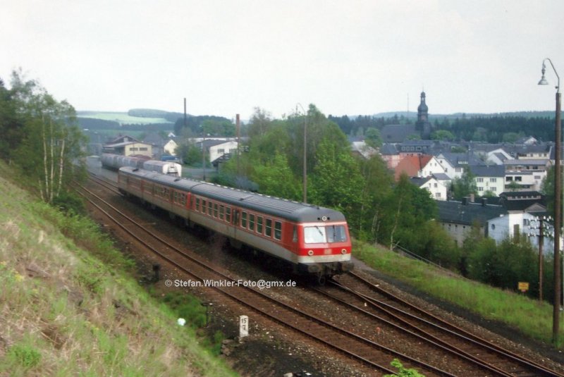 Frühjahr 1987 fährt der 614014 aus dem Bf. Selbitz Richtung Naila aus. Hinten gibt es noch 2 Gütergleise, die sogar benutzt wurden. Der Kühlwagenzug stand lange Monate dort. Hinten grüsst die Stadtkirche, rechts unten das Ortsschild an der Straße...  Historisches Motiv aus dem Diaarchiv, Nr. 19R8