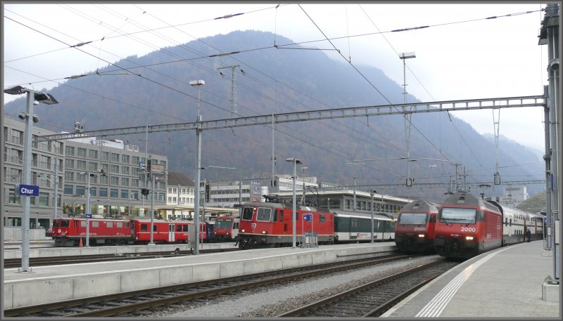 Ge 4/4 I der RhB, RBDe 560 NPZ, Re 4/4 II und 2x Re 460 aufgereiht im Bahnhof Chur, dahinter Brambresch, der Churer Hausberg erschlossen durch die neu gebaute Luftseilbahn. (30.10.2007)