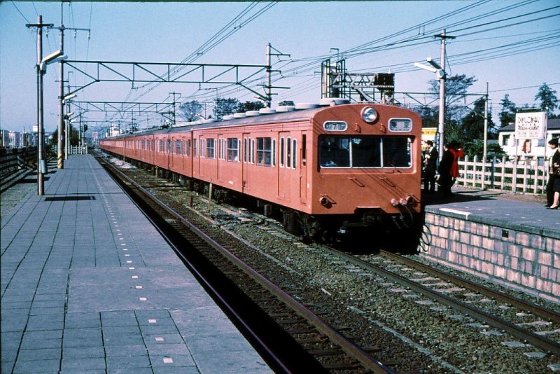 GLEICHSTROMZUEGE: Diese haben die Nummerngruppen 100/200/300 ff. Die Pazifikküste (Tôkaidô) und die Grossagglomerationen (Tokyo-Nagoya-Kansai,d.h.die Städte Kyoto,Osaka,Kobe)sind längst mit Gleichstrom 1500V elektrifiziert.Die 1957 gebauten Züge Serie 101, erstmals mit Kardanwellen-Antrieb und Verteilung der Apparate auf verschiedene Wagen, läuten ein neues Zeitalter ein. Erstmals auch Anstrich für jede Linie unterschiedlich. 1535 Wagen Serie 101 gebaut; im Einsatz bis 2003.Hier ist - noch ohne Klimaanlage - ein Zug Serie 101 (Frontwagen KUHA 101-22) in Tokyo-Higashi Koganei; Anstrich orange für die Chûô-Linie. 5.November 1972. 