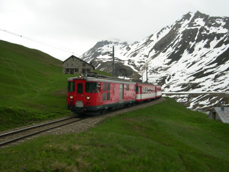 Gotthard 2008 - Als R 835 Disentis-Andermatt verggt sich am 24.05.2008 dieser, von Deh 23 gefhrte Zug kurz vor der Station Ntschen. Von hier braucht der Zug noch 14 min nach Andermatt. Sein Ziel verliert er dabei selten aus den Augen. Der Ort ist von hier oben aus von allen Seiten prsent!