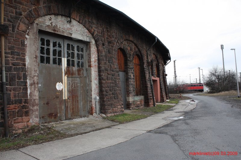 Groer Ringlokschuppen in Mz-Bischofsheim. Die Umfassungswnde des Gebudes sind aus massivem rotem Sandstein gemauert und bemerkenswert gestaltet. Je zwei Rundbogenfenster sind mit Rundbgen zusammengefasst. Auf der Innenseite ruhen die Dachbinder auf Stahlprofilsttzen. Die genieteten Stahltore sind
teilweise durch Mauerwerk ersetzt.