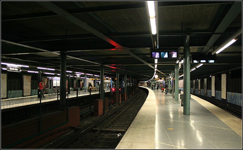 Grüne und Rote Linien, Station  Gamla stan  - 

An dieser Station kommen die Gleise aus Richtung T-Centralen wieder an die Oberfläche, nachdem das Gewässer  Norrström  unterfahren haben. Dabei verschlingen sich die Gleise vom Gegenrichtungsbetrieb in Richtungsbetrieb. Im viergleisigen Bahnhof Gamla stan kann also zwischen der Roten und Grüen Linie in grob gleicher Himmelsrichtung bahnsteiggleich gewechselt werden. Über dem Bahnhof verläuft eine Hauptverkehrsstraße, daher macht er einen fast unterirdischen Eindruck. Die Aufnahme entstand zudem bei Dunkelheit, daher sind die seitlichen Öffnungen nicht erkennbar. 

29.08.2007 (M)