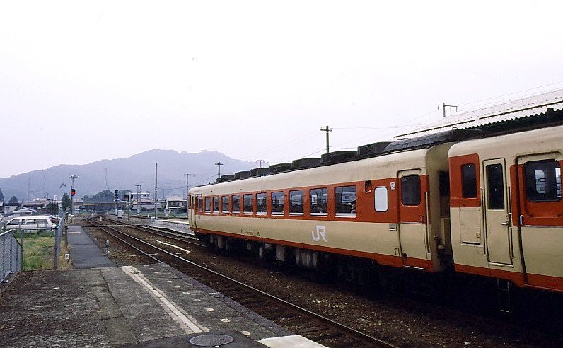 Grundstruktur des japanischen Eisenbahnnetzes (4): Im April 1987 übernahmen 6 JR (Japan Railways-) Personenverkehrsgesellschaften das Erbe der alten Staatsbahn:　nun trugen die Fahrzeuge gross das  JR -Signet (wie im Bild: Dieseltriebwagen KIHA 58 7203 in Nishi-Maizuru, 6.September 1994). Die 6 JR-Gesellschaften haben jetzt alle ihren eigenen Fahrzeugpark (1067mm-Spur Fahrzeuge sowie – gegebenenfalls - 1435mm-Spur Shinkansen-Fahrzeuge) und ihr eigenes Territorium. Die 6 JR-Gesellschaften sind - auf der Hauptinsel (Honshû) - JR OSTJAPAN (Osten und Nordosten, einschl. Ballungsraum Tokyo), JR TÔKAI ( Ostmeerstrasse , d.h.zentrale Pazifikküste, einschl.Ballungsraum Nagoya;auch JR CENTRAL genannt), JR WESTJAPAN (Westen einschl.Ballungsraum um Kobe,Osaka und Kyoto), ferner die 3 Inselbahnen:Im Westen JR KYÛSHÛ und JR SHIKOKU; im Norden JR HOKKAIDO. 